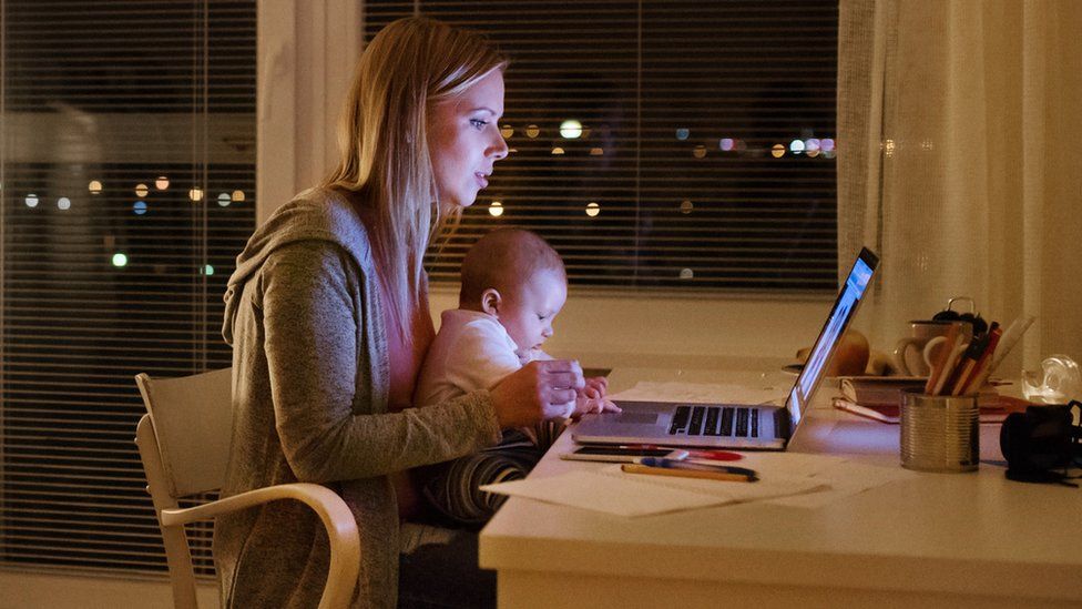 Mother with son in the arms, working on laptop