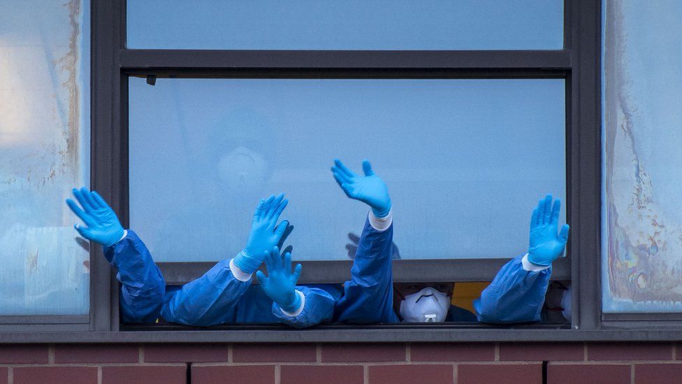 NHS staff wave out a window