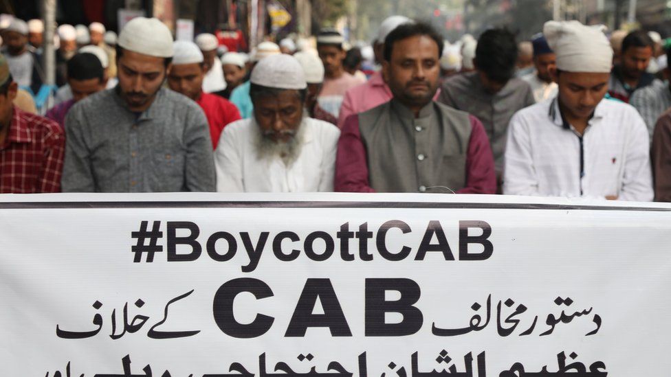 Protesters offering Friday prayers in front of a banner reading #BoycottCAB