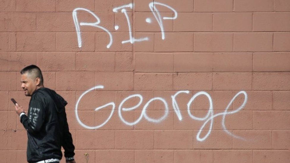 Un ciudadano camina frente a un mensaje de despedida a George Floyd