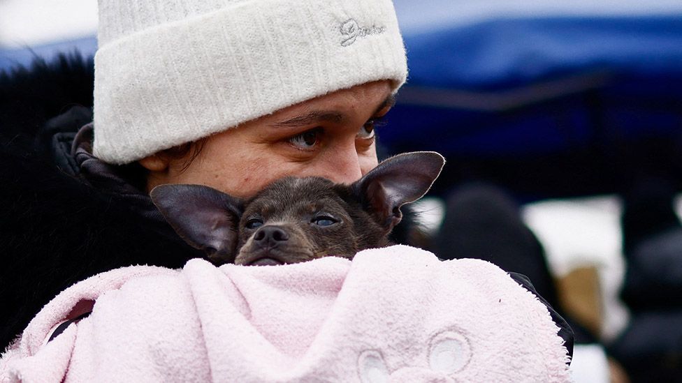 A woman fleeing the Russian invasion of Ukraine holds a dog at a temporary camp in Przemysl, Poland, 28 February 2022