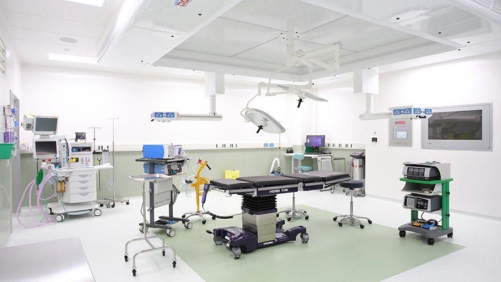 An operating theatre, painted mostly white with lots of equipment inside