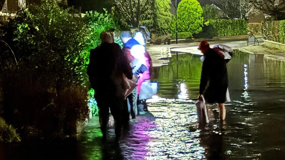 People walking through flood water