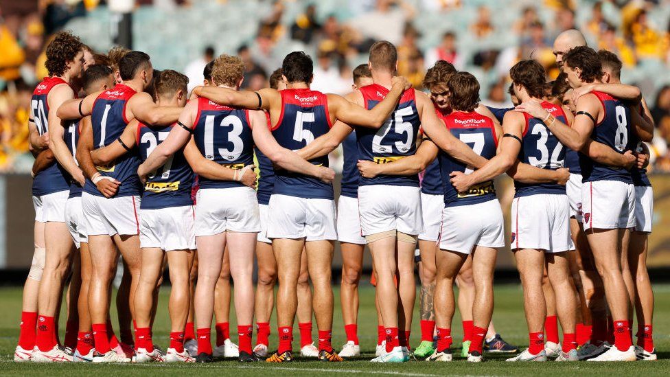 Melbourne Demons players in a team huddle