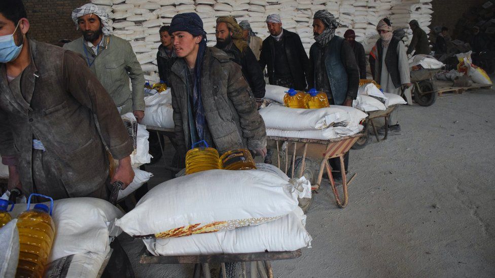 Men wheeling bags of grain and oil in Afghanistan