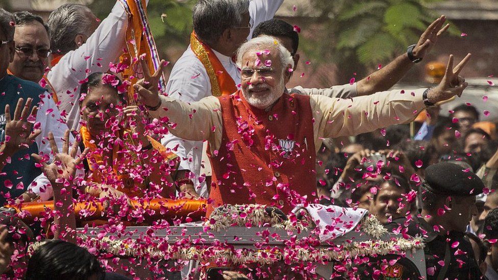 Supporters throw flower petals as Narendra Modi rides in an open jeep in Vadodra
