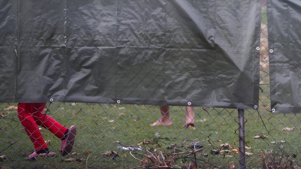 A child is seen running behind a sheet blocking a view of the Manston Processing Centre