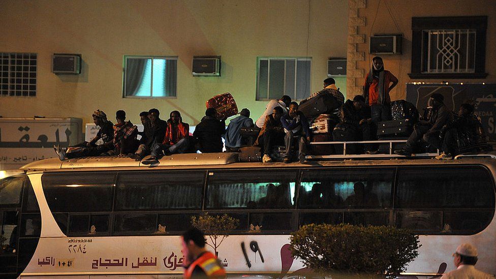 Illegal migrants sit on the roof of a police bus with their belongings on November 13, 2013 before being transferred to a center in the capital Riyadh ahead of their deportatio