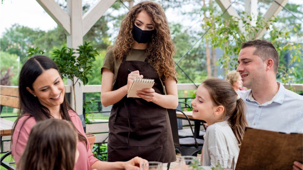Family with waitress in mask
