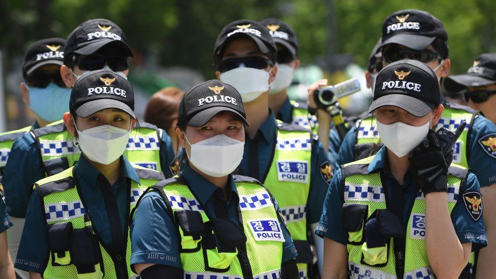 Police officers wearing face masks stand guard during a rally by anti-Trump protesters near the US embassy in Seoul
