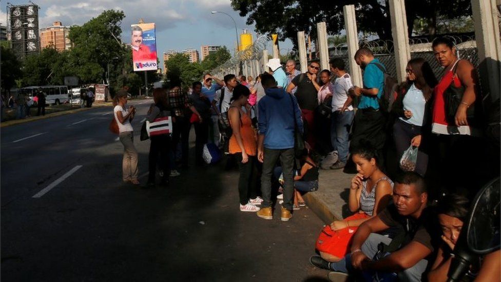 Venezuela's President Nicolas Maduro campaign posters for the 2018 presidential elections is seen in the street as people wait for a bus in Caracas, Venezuela May 11, 201
