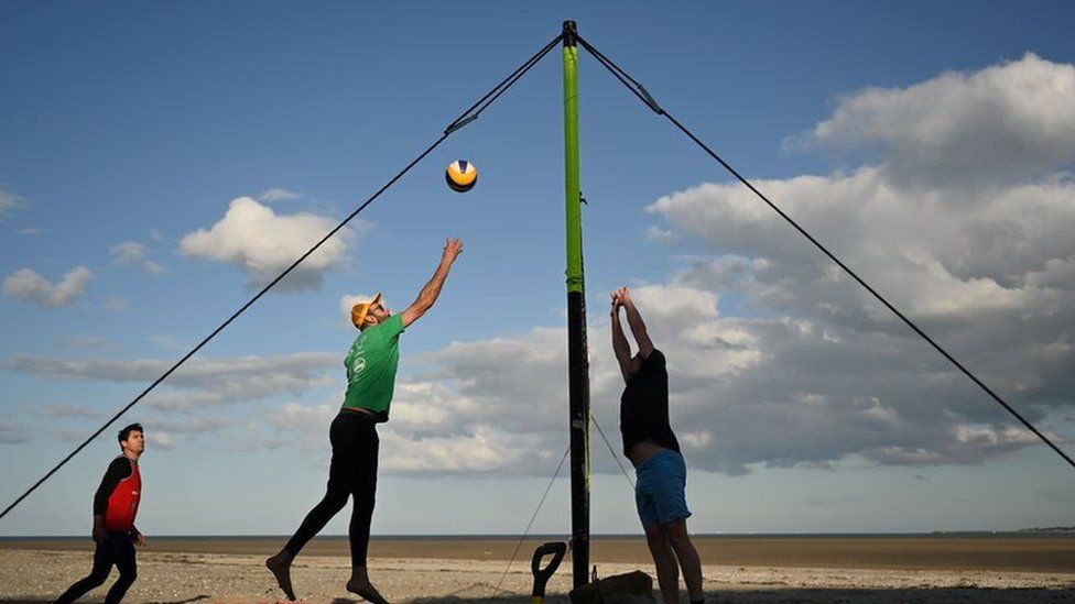 Люди играют в волейбол на пляже Пулбег в Дублине