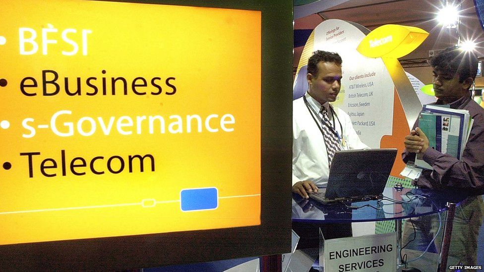 A visitor (R) takes a look at software products in a stand of the 'IT.COM 2002' internet fair in Bangalore, 29 October 2002.