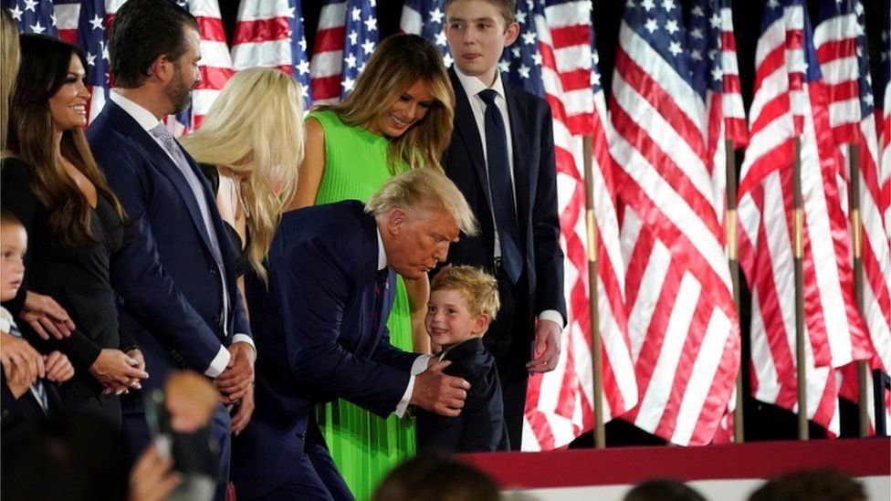 U.S. President Donald Trump grabs one of his grandchildren as he, U.S. first lady Melania Trump and their extended family