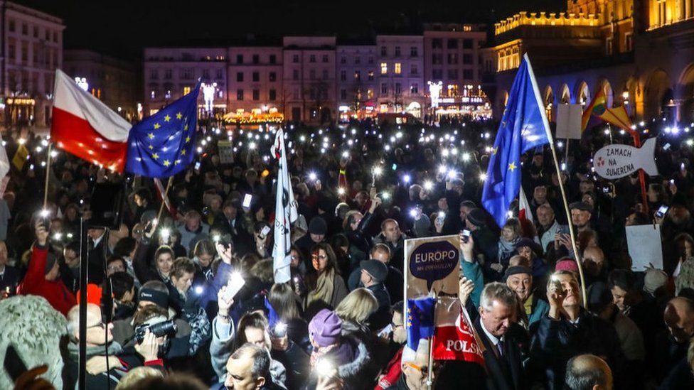 Polish protesters against a controversial new judicial reform law hold copies of the constitution and EU flags in Warsaw