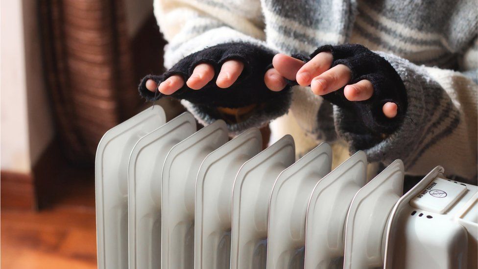 Person's hands warming above a radiator