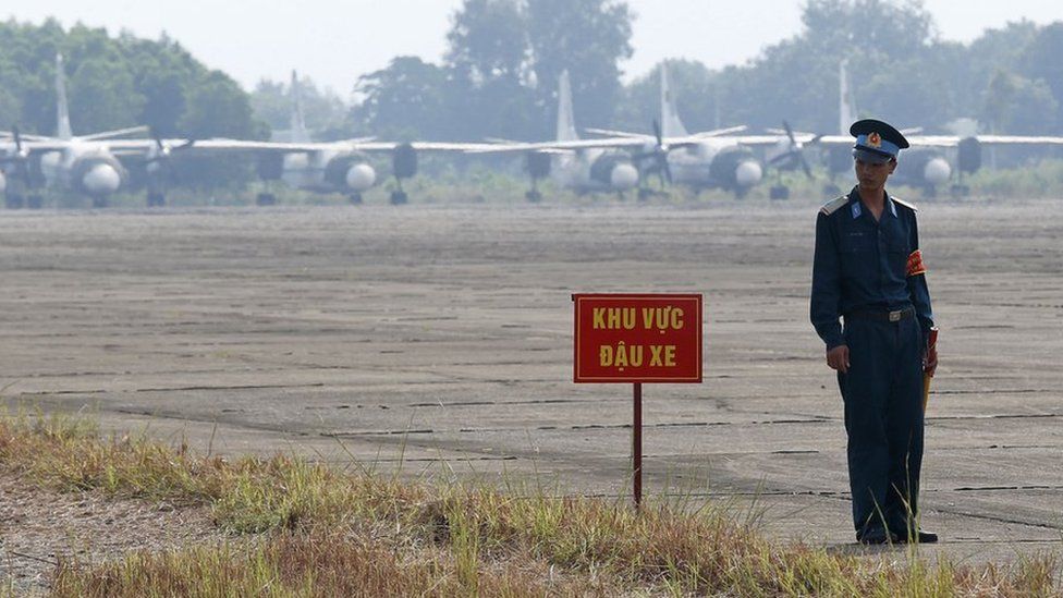 Vietnamese soldier stands next to a hazardous warning sign by a runway at Bien Hoa air base