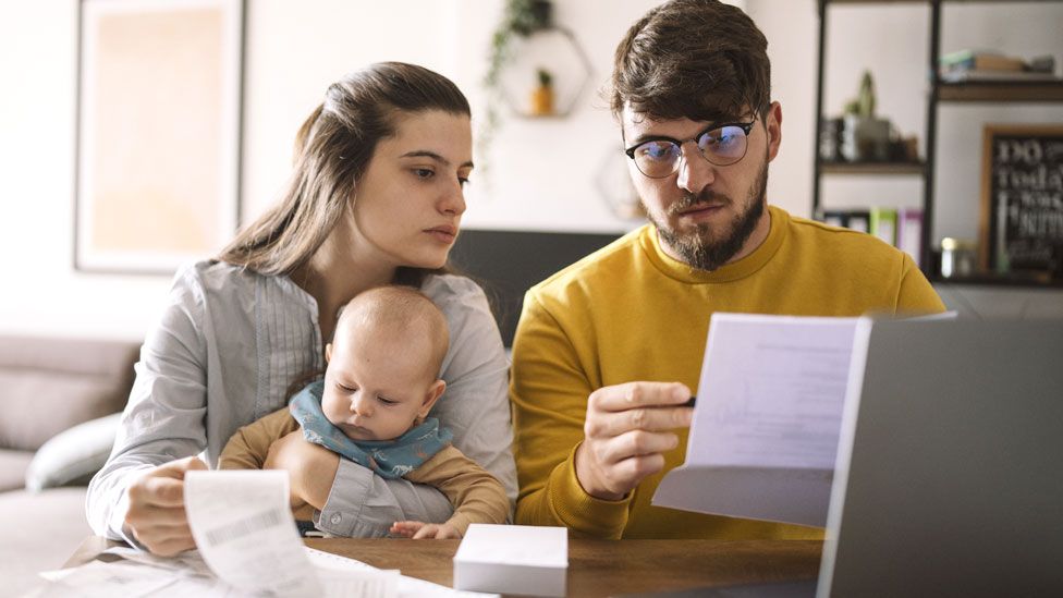 A couple with their baby looking at bills