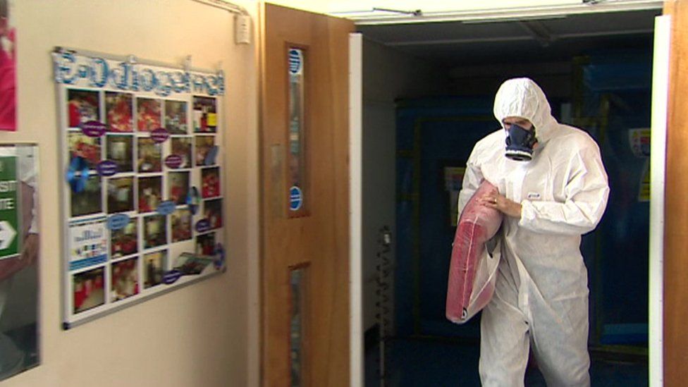 A worker removes asbestos from a school