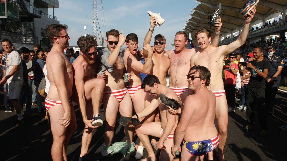 Australian men celebrate in Budgy Smuggler-brand swimsuits decorated with the Malaysian flag at the conclusion of the Malaysian Formula One Grand Prix in Sepang, Malaysia.