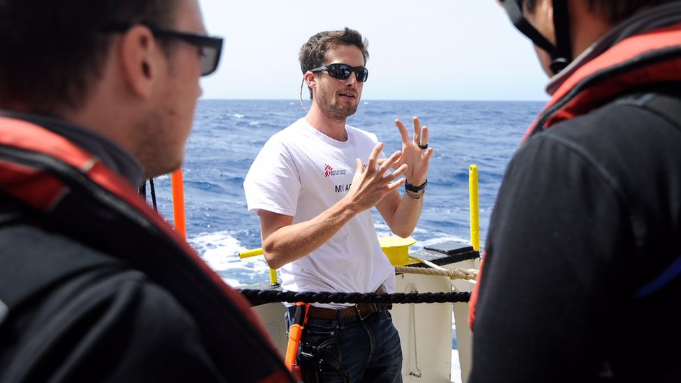 Max Avis gestures to crew members onboard the ship