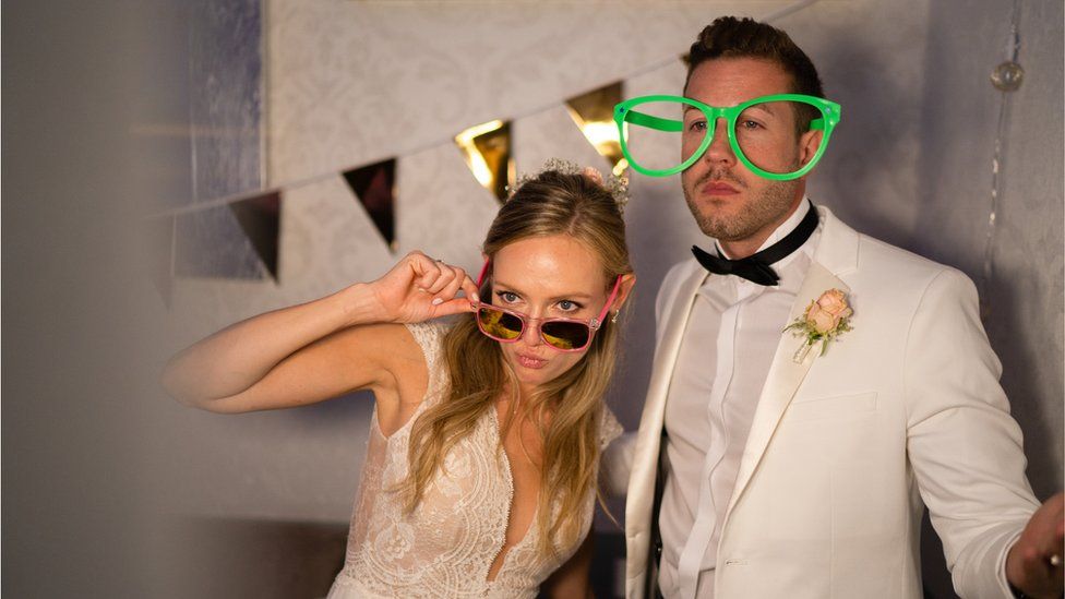 A newlywed couple in a photo booth at their wedding reception