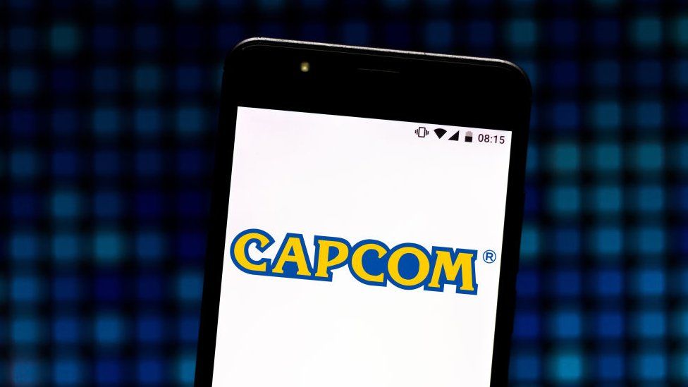 Логотип Capcom виден на экране смартфона на текстурированном фоне пикселей