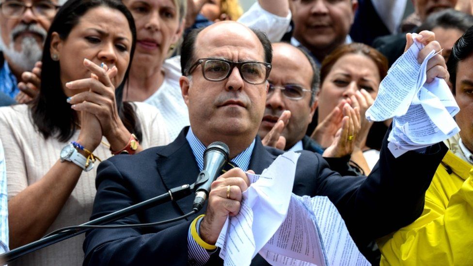 The president of Venezuela's National Assembly Julio Borges, tears a copy of a sentence of Venezuela's Supreme Court granting itself legislative powers, as he speaks during a press conference in Caracas
