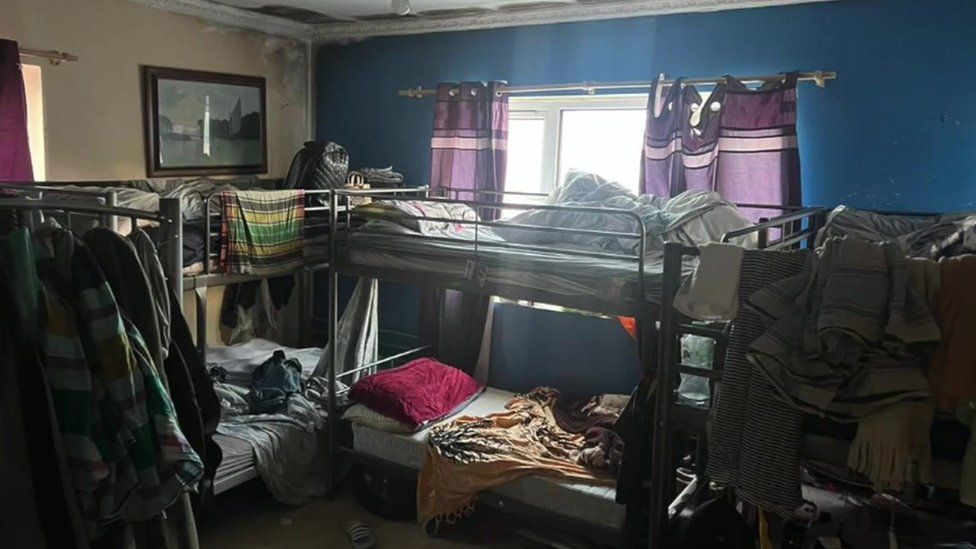 Image showing 3 single bunkbeds surrounded by possessions in a small room.