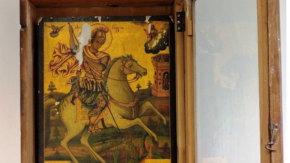 a Byzantine image of Saint George, in recognisable golden painting style, sits in a wooden frame