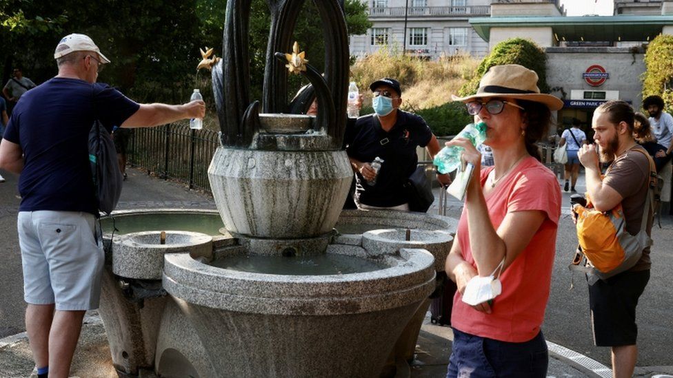 People collect water from a fountain in Green Park in London