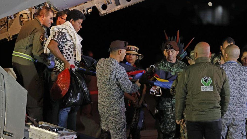 Одного из детей уносят с военного самолета в Боготе на носилках