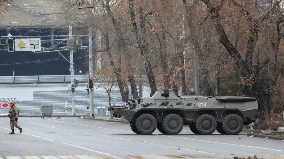 Казахстанский военнослужащий идет возле бронетранспортера в Алматы