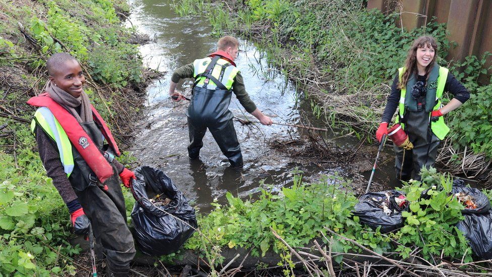 Three people clearing a waterway