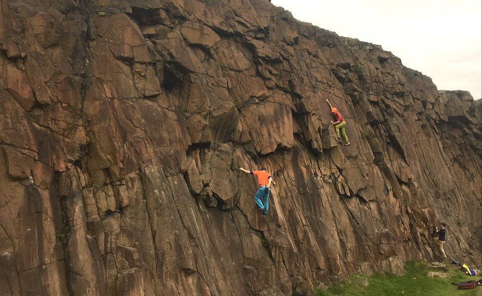 Stephen Venables wearing green trousers climbing Salisbury Crags
