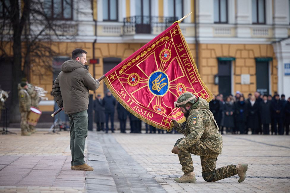 Президент Украины Владимир Зеленский передает флаг военнослужащему во время церемонии, посвященной первой годовщине российского вторжения в Украину, на фоне нападения России на Украину, в Киеве, Украина 24 февраля 2023 г.