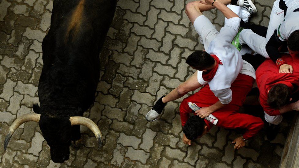 Runners sprint ahead of Fuente Ymbro fighting bulls during the fourth running of the bulls at the San Fermin festival in Pamplona, northern Spain, 10 July