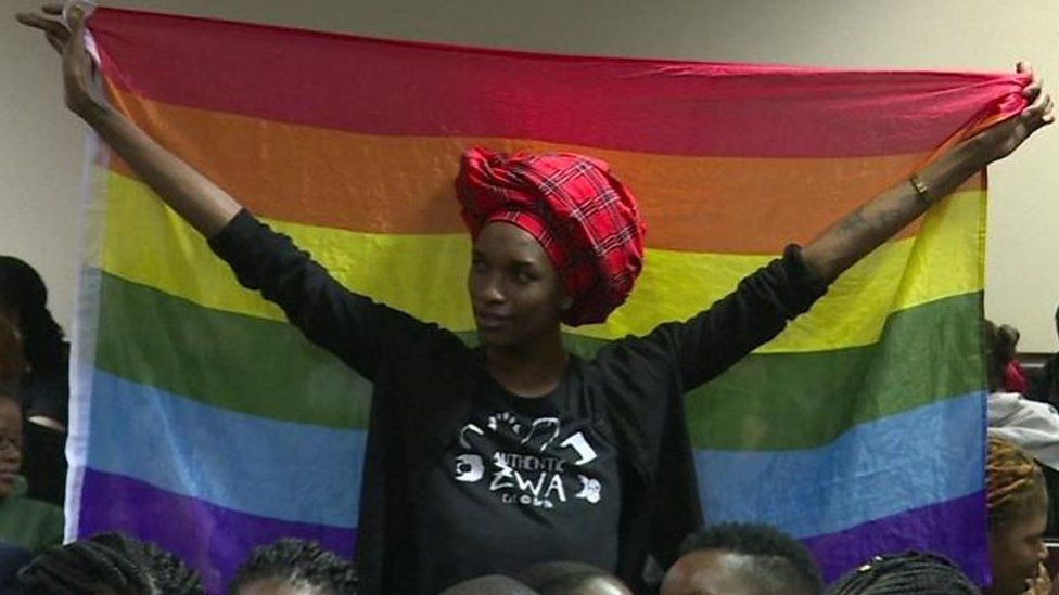 A woman holding a rainbow flag