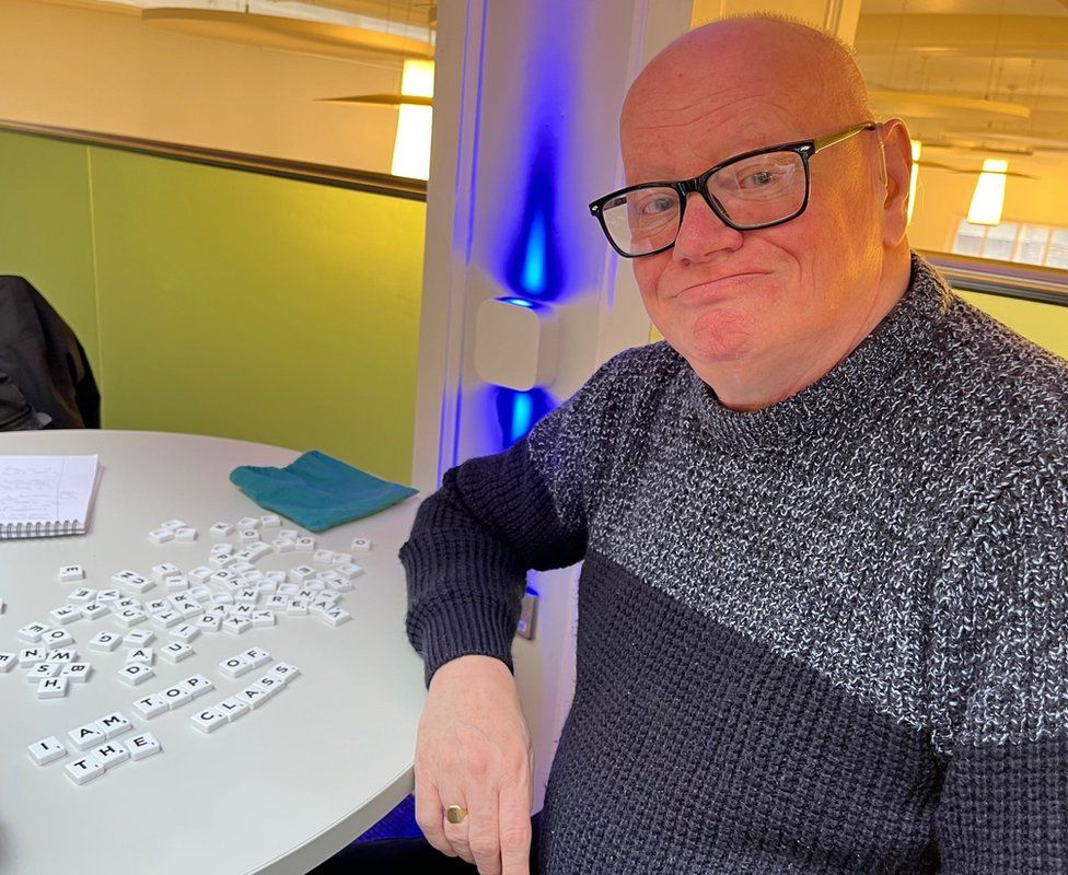 Graham pictured next to a message written using Scrabble tiles stating 'I am top of the class'