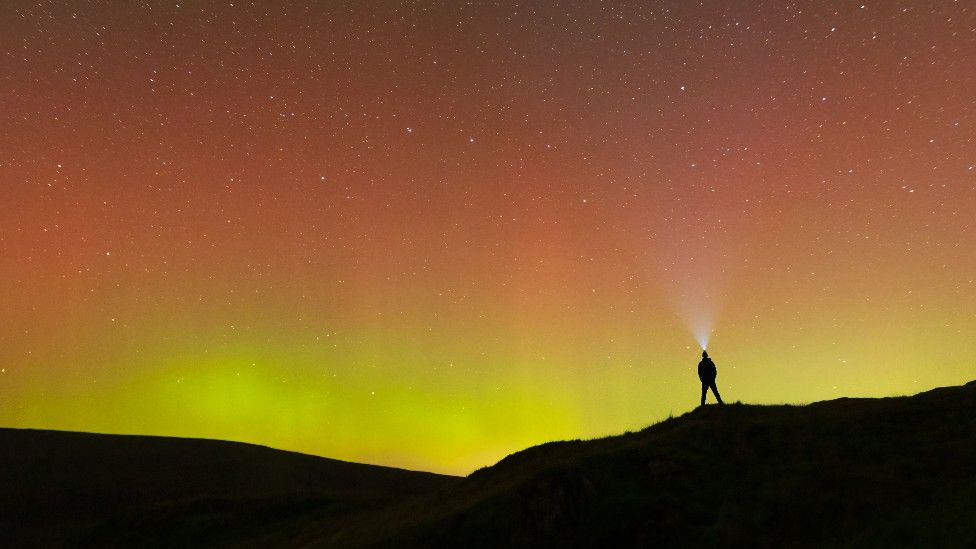 The Northern Lights in Haweswater, Cumbria with silhouette of person