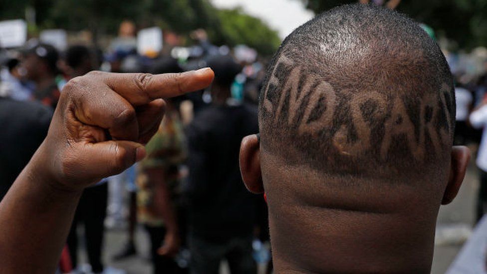A Nigerian based in South Africa shows the middle finger and words "EndSars" shaved on his head during a protest outside the Nigerian embassy in Pretoria on October 21, 2020 in solidarity with Nigerian youth who are demanding an end to police brutality in the form of The Nigerian Police Force Unit, Special Anti-Robbery Squad (SARS).