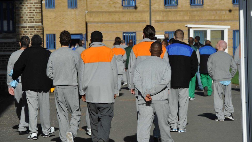 Male prisoners seen from behind in the exercise yard of Wormwood Scrubs, a prison in London