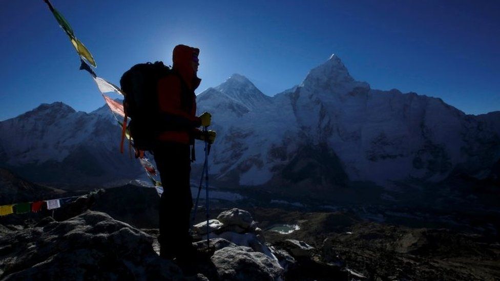 A hiker is seen in side-on silhouette on Everest