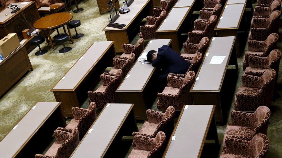 A lawmaker rests as he waits for the start of the upper house committee session on Wednesday night - it was eventually abandoned at 3:50am