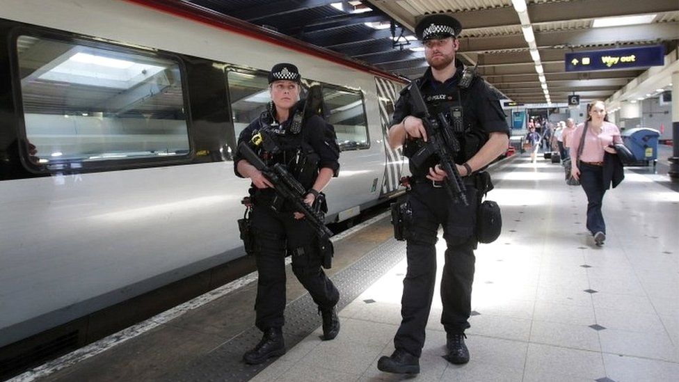 Armed British Transport Police Specialist Operations officers on the platform before boarding a Virgin train to Birmingham New Street at Euston station in London