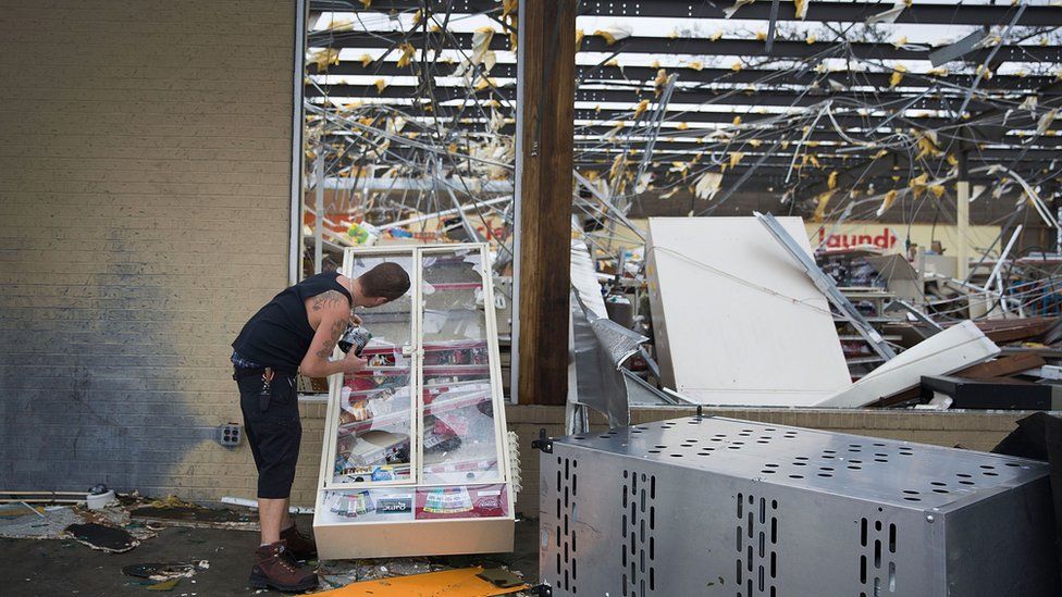 A man takes some tobacco products from a damaged store in Panama City, Florida, after Hurricane Michael passed through the area, 10 October 2018