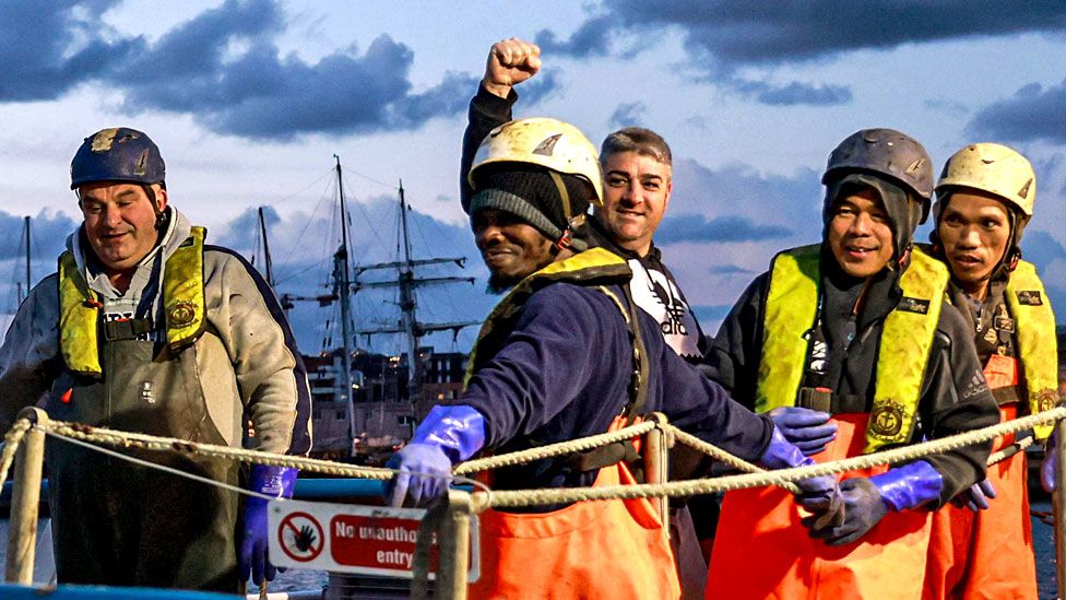 The crew of the Scottish scallop trawler "Cornelis-Gert Jan" stand on the deck as they leave the northern French port of Le Havre