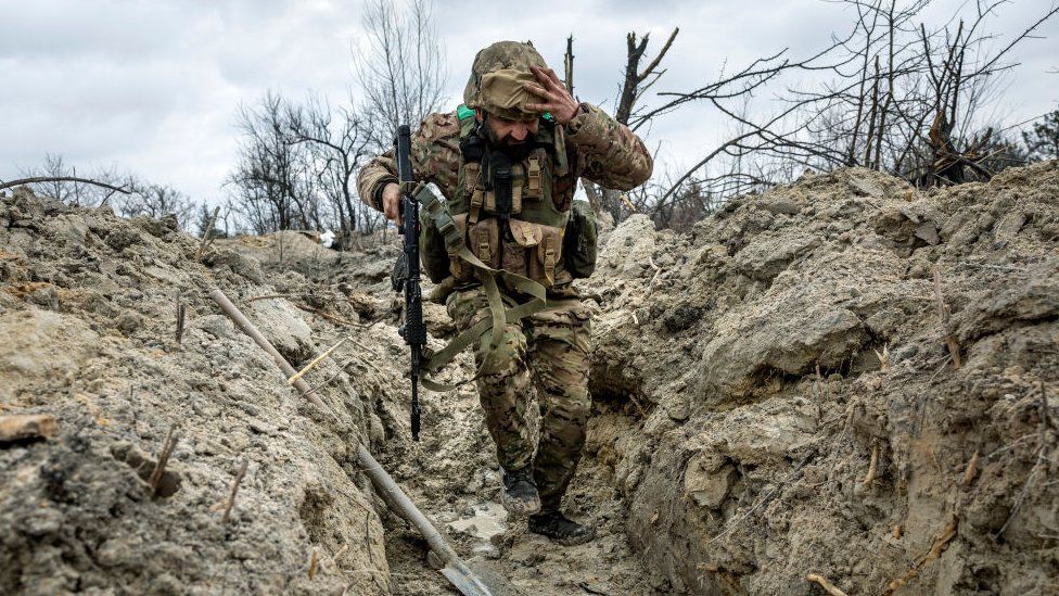 A Ukrainian soldier runs into a trench outside Bakhmut