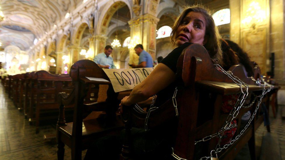 Relatives of victims of human rights abuses during the former dictatorship of Augusto Pinochet chain themselves to pews at the Cathedral of Santiago to protest against a mass taking place in the special prison for human right abusers called "Punta Peuco", acccording to local media, in Santiago, Chile
