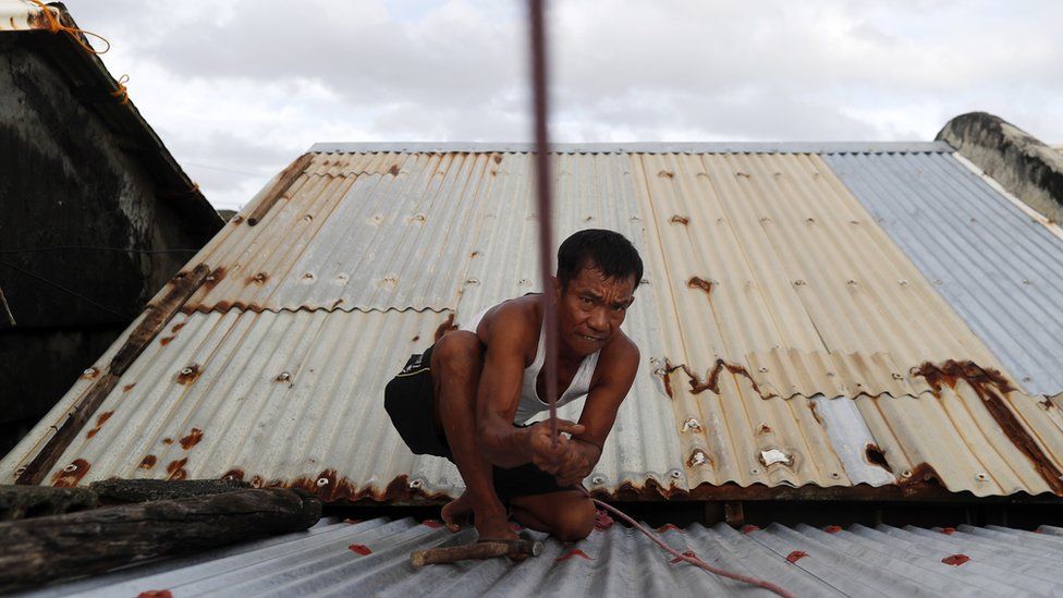 A Filipino villager secures the roof of a house in the town of Aparri, Cagayan province, Philippines
